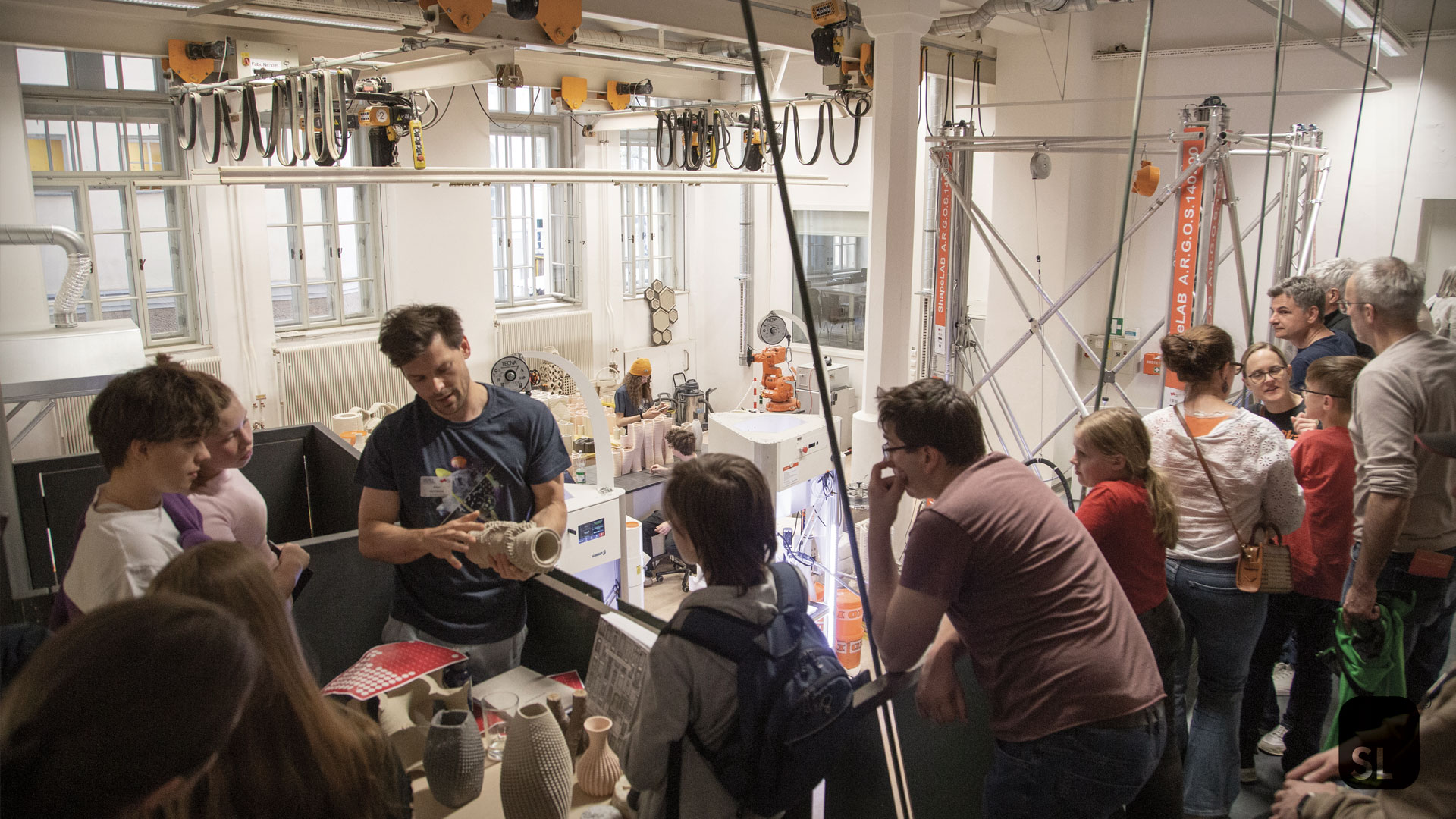 scientist shows a 3D printed object at members of the public visiting during Lange Nacht der Forschung