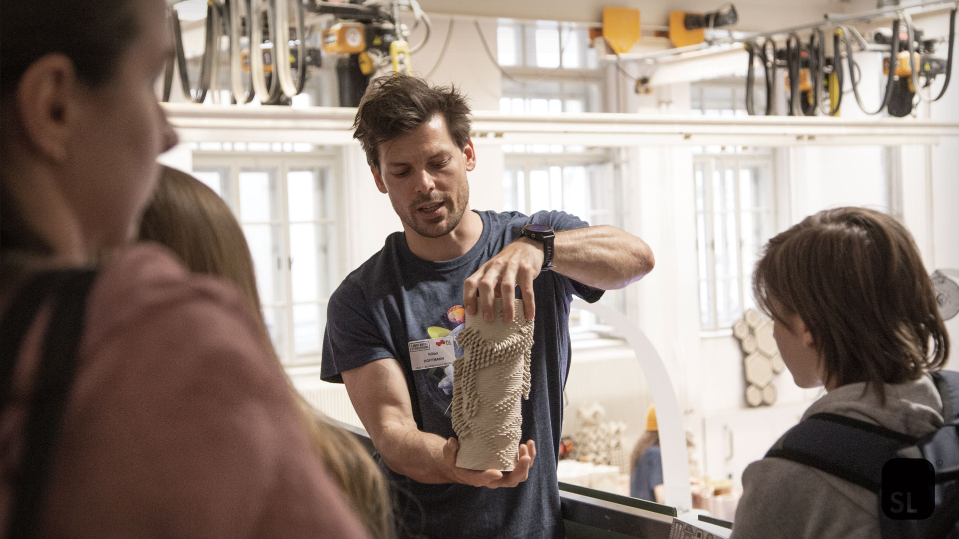 scientist showing a 3D printed object to visitors at the Lange Nacht der Forschung